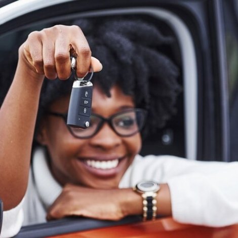 young-african-american-woman-sits-inside-new-modern-car-shows-keys_146671-27564